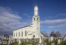 L'église catholique Saint-Joseph. Le clocher surplombe le bâtiment de style Greek Revival, italianisant et fédéral. Au premier plan, des tombes entourent l'édifice.