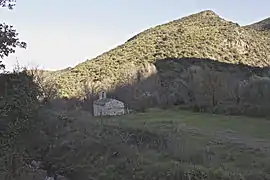 Petite église dans l'ombre. À l'arrière plan, une petite montagne éclairée par le soleil rasant.
