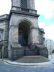 Bâtiment de pierre. Haut porche précédé d'un vaste perron