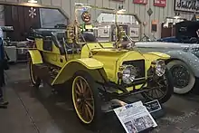 Photo d'une voiture ancienne jaune, prise légèrement du côté avant gauche.
