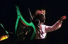 Stivell derrière sa harpe avec une cornemuse dans les bras