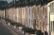 Yellow stone terraced houses alongside a steep road.