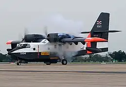 vue de profil d'un canadair blanc et noir, avec du rouge sur les ailes et sur la queue au décollage.
