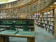 Vue d'une partie de la salle de lecture avec de grandes bibliothèques et des tables de lecture.