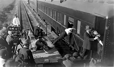 Tournage d'une scène de cascade pour le film de Reginald Barker, The Old Nest (1921). Devant les deux 2709 côte à côte, le comédien Rupert Hughes va éjecter du train (en marche) la comédienne Helene Chadwick qui sera reçue entre la voiture et le wagon plat transportant l'équipe, sur un bâti en bois avec l'aide musclée de deux assistants.