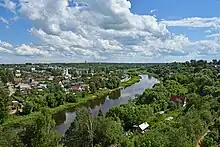 Photographie d'une rivière passant dans un paysage vert avec de nombreuses maisons.