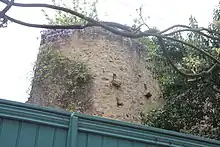 Vue d'une tour à l'arrière-plan, au-delà d'un portail. La tour est couverte en partie haute de fleurs.