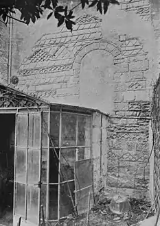 Photographie en noir et blanc d'un décor de dessins géométriques et briques sur un mur en pierre.