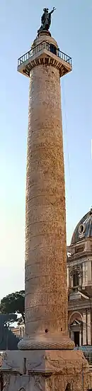 haute colonne blanche, droite et décorée d'une spirale, surmontée d'une petite plate-forme carrée où repose une statue d'homme.