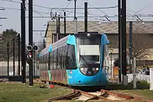 Deux rames Citadis Dualis entrent en gare de Haluchère-Batignolles à Nantes le jour de l'inauguration. Elles franchissent le croisement à niveau avec la ligne du tramway nantais.