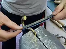 Polissage d'une pièce de bronze à l'aide d'un papier émeri abrasif pour rendre la surface plus brillante