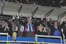 Photo de Jacques Chirac et Michel Platini levant les bras dans une tribune de stade de football.