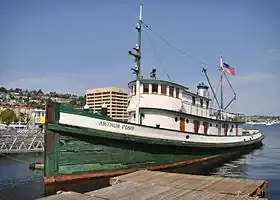 Photo du Arthur Foss : bateau en bois amarré le long d'un quai flottant. Sa coque est verte avec une bande blanche dans laquelle est inscrite Arthur Foss. La superstructure est peinte en blanc. Le drapeau américain est hissé au mât arrière.