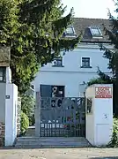 Photo couleur d'une entrée de jardin avec une façade claire derrière