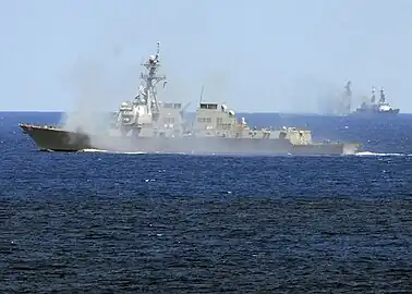 L'USS Oscar Austin faisant feu contre la cible (au fond).