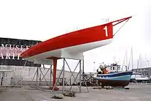 Un voilier de régate reposant sur un ber statique.