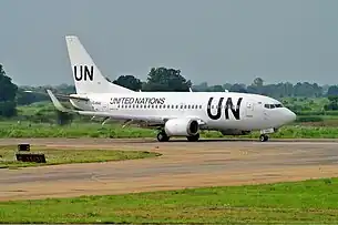 Un Boeing 737, roulant dans une aéroport, opéré par les Nations Unies, étant blanc avec des écritures imposantes "UN" noir