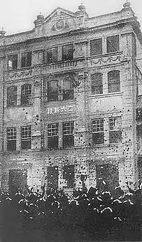 photo d'un bâtiment. Devant lui est réunie une foule importante.