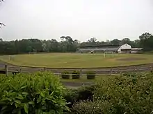Photographie en couleurs d'un terrain de sports bordé par de longues tribunes couvertes.