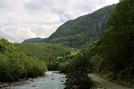 Bâtiments de ferme rouges près d'un petit pré dans une vallée boisée.