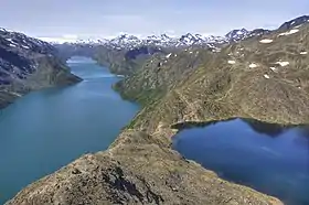Grand lac allongé aux eaux turquoises vu depuis une arrête rocheuse près d'un petit lac.