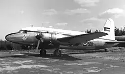 photographie en noir et blanc montrant de côté un avion bimoteur stationné sur un aéroport