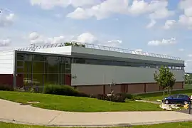 Vue d'un grand bâtiment en panneaux ondulés et en verre ; toit en terrasse.