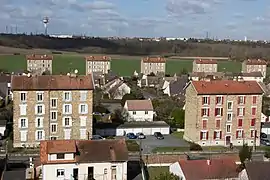 Vue de petits immeubles en pierre et d'un espace agricole.