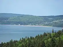 Photographie de plusieurs maisons dans une baie bordée de collines couvertes d'arbres