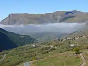 La route du col du Lautaret et le hameau des Cours ; en fond d'image, le plateau d'Emparis.