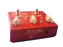 pédale d'effet rouge avec trois boutons blancs et la signature de Joe Satriani sur le côté