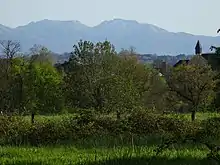 Photographie en couleurs d'une église et de montagnes au fond.