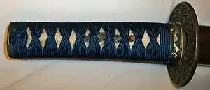 Exemple de poignée, le tsuka. On distingue sous le tressage la peau de raie et un menuki.