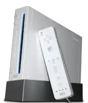 Une console de jeux vidéo Wii, dressée à la verticale sur un socle. Une Wiimote, contrôleur de jeu semblable à une télécommande, est posée contre la console.