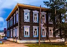 Photographie d'un bâtiment en bois marron avec les cadres des fenêtres bleues possédant deux étages.