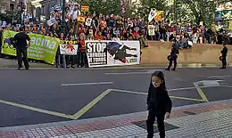 Au premier plan une petite fille, et en arrière-plan des manifestants tenant diverses banderolles.